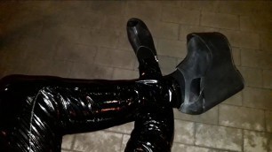 a crossdresser in high wedge platform shoes and latex leggings is walking the streets at night